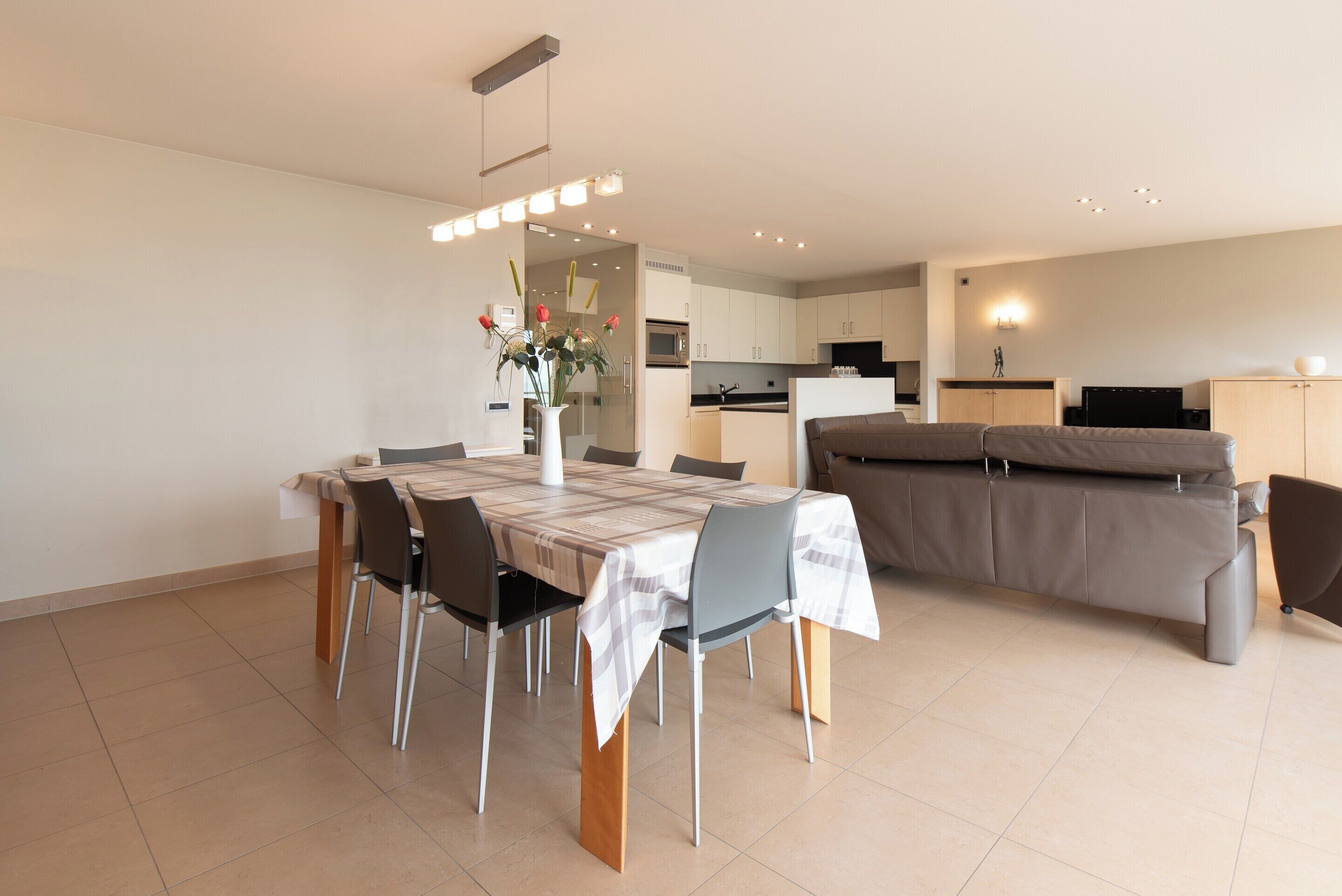 A modern living space with a dining area, kitchen, and seating area.