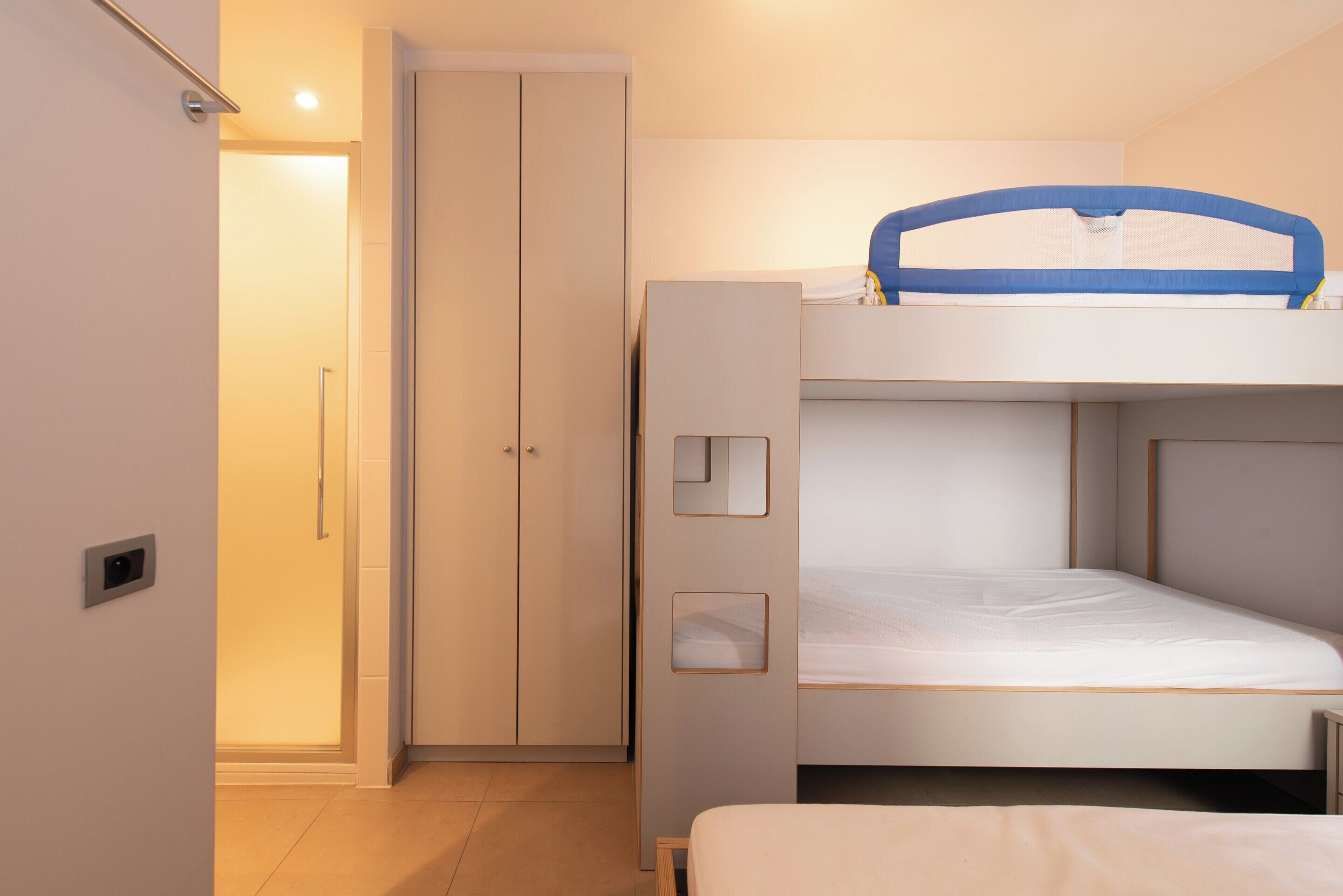 Une chambre avec un lit superposé, une armoire et une porte.