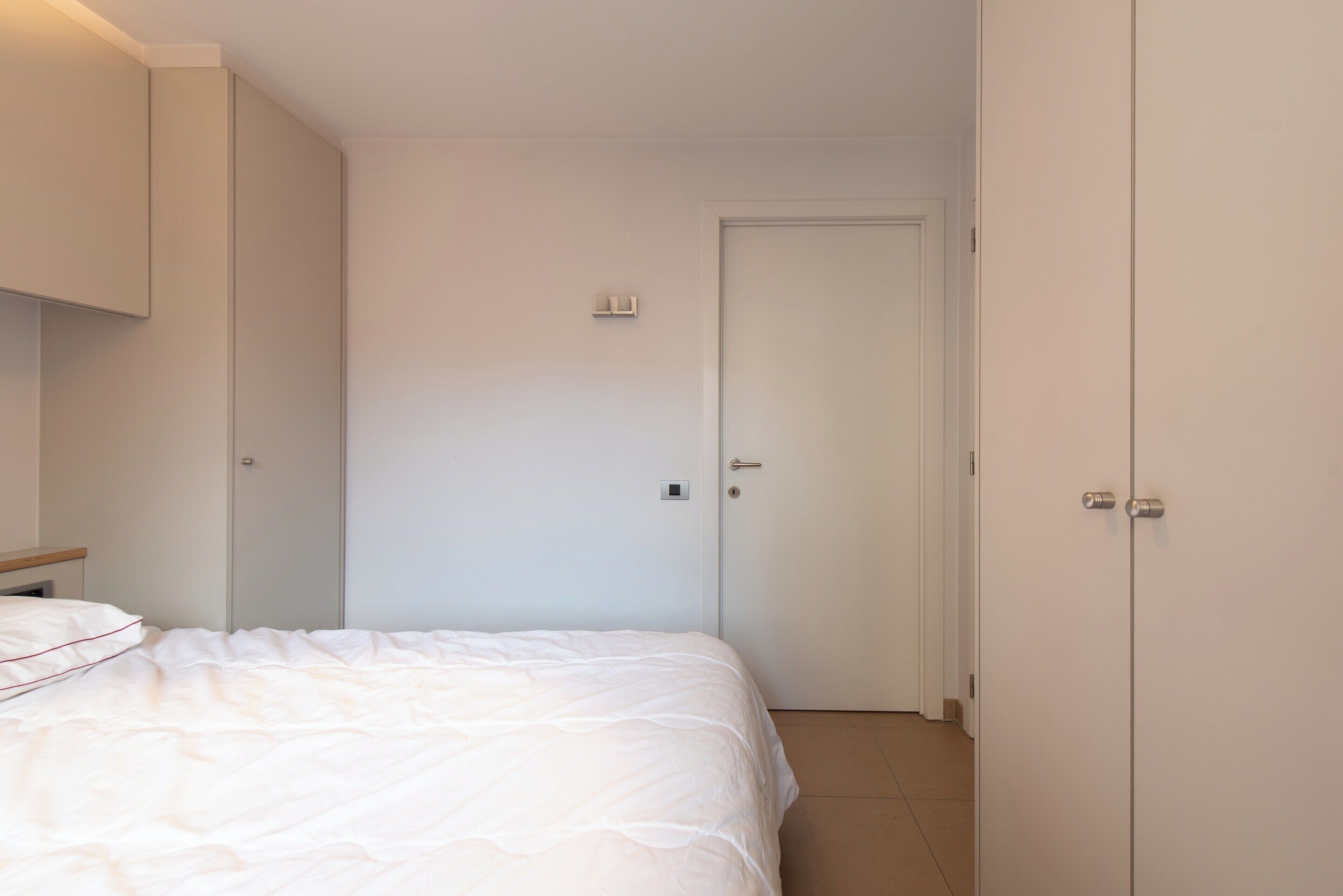 A bedroom with a bed, a wardrobe, and a door.
