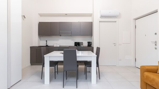 A compact kitchen with a white table and chairs, a microwave, and a coffee maker. - Italianway - Pianell 5 A (Milan)