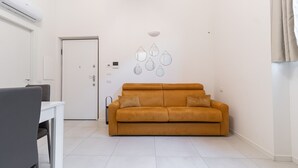 A modern living room with a sofa, a dining table, and a white door. - Italianway - Pianell 5 A (Milan)