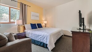 Une chambre d’hôtel avec un lit, un bureau, une chaise et un téléviseur.