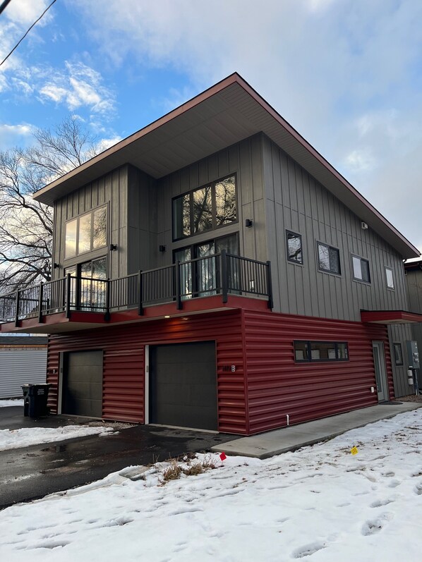 En toetages bygning med balkon, store vinduer og garage.