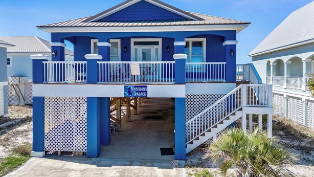A two-story beach house with a balcony and a covered entryway.