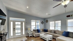 A spacious living room with a large sofa, a coffee table, and a ceiling fan.