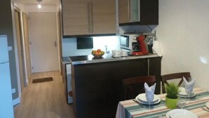 A compact kitchen with a microwave, a red coffee maker, and a bowl of fruit on the counter. - Lovely apartment near city center (Canet-en-Roussillon)