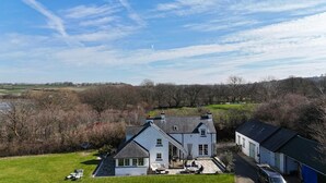 A large house with a spacious patio, surrounded by trees and a view of the countryside. - Ol y Don, Newport - Three Bedroom Cottage, Sleeps 6 (Newport)