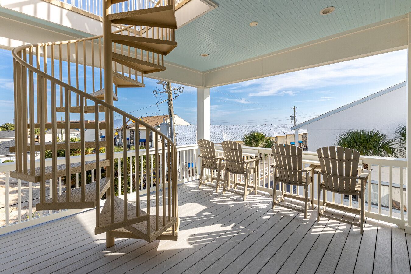 A wooden deck with a spiral staircase, outdoor seating, and a view of the sea.