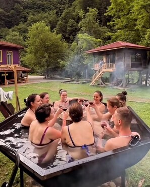A group of people in a hot tub outdoors surrounded by trees and a wooden structure. - Nordic Hotel (Camlihemsin)