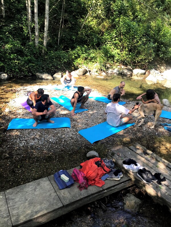 Un grupo de personas sobre esterillas azules al aire libre, rodeado de follaje y rocas.