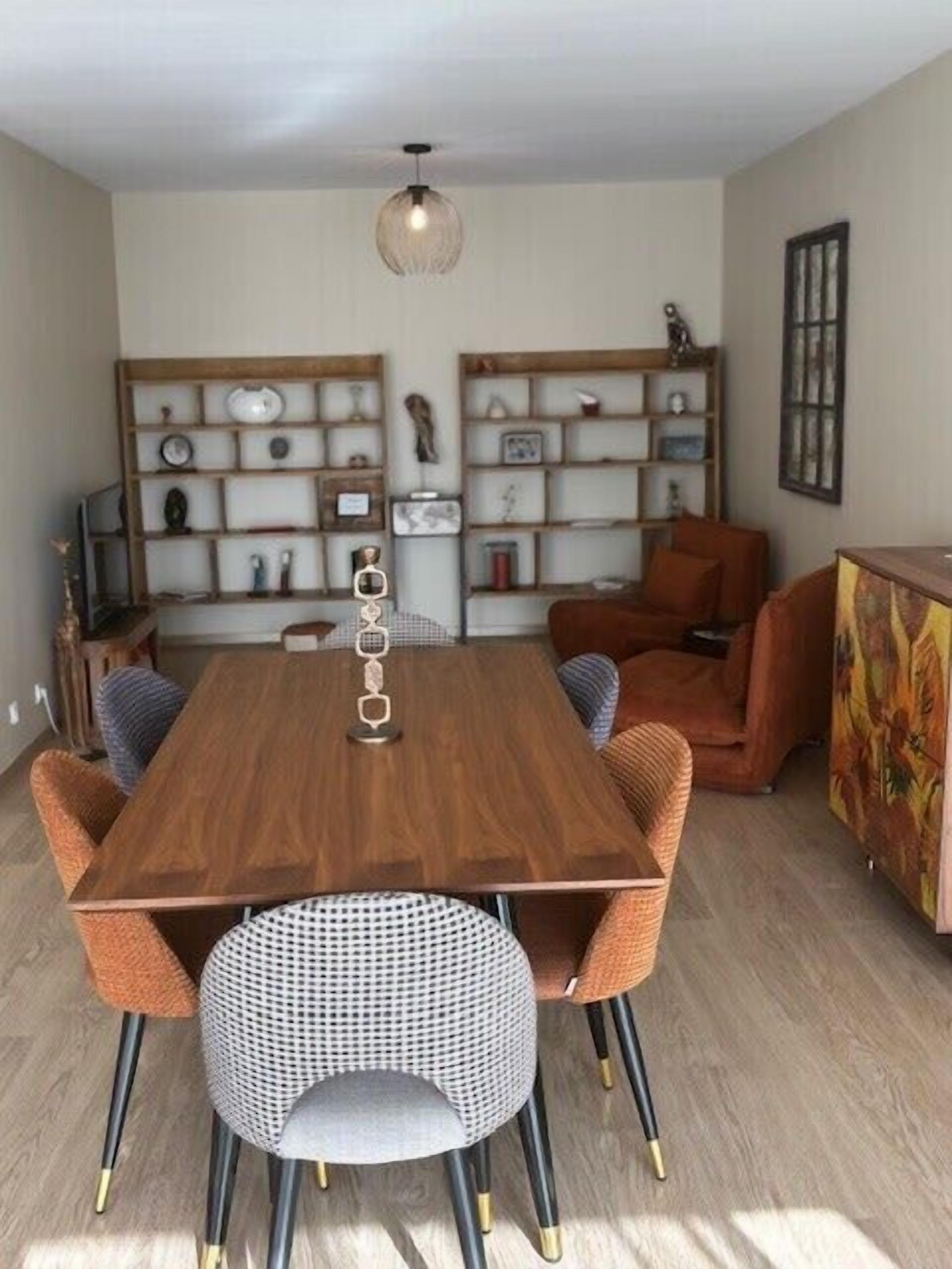 A dining area with a wooden table, four chairs, and a hanging light fixture.