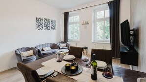 A modern living room with a dining table set for a meal, a sofa, and a television.
