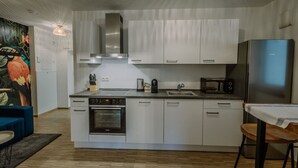 A modern kitchen with white cabinets, stainless steel appliances, and a large island. - Passau Apartment|Singles-Couples-Groups|Central (Passau)