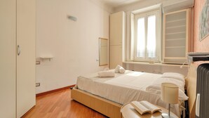 A bedroom with a bed, bedside table, lamp, and a window with curtains. - JOIVY Bright flat near the city centre  (Milan)