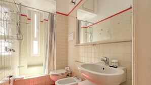 A modern bathroom with a bathtub, two toilets, a large sink, and a shower area. - JOIVY Bright flat near the city centre  (Milan)