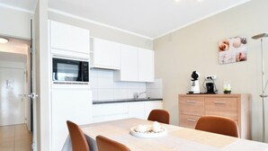 A modern kitchen with white cabinets, a microwave, and a coffee maker on the counter. - Studio in Middelkerke Near Sea Wall (Middelkerke)