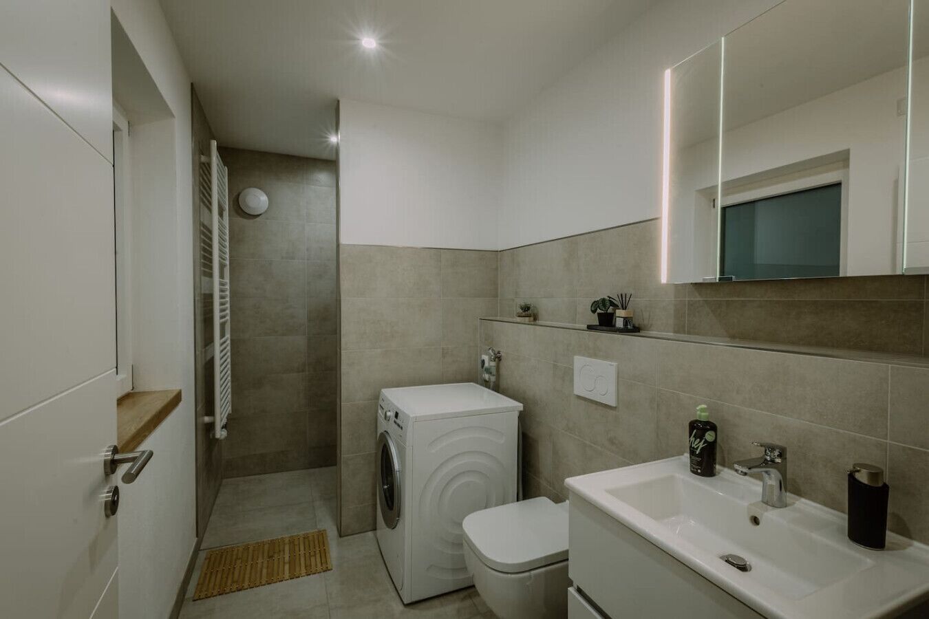 Un baño pequeño con lavadora, inodoro y lavamanos.