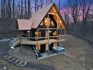 Une cabane avec une façade en bois, un balcon et un jacuzzi.