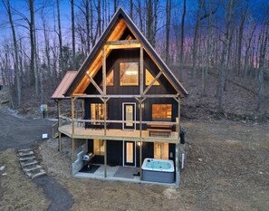 A cabin with a balcony, a hot tub, and a deck area.