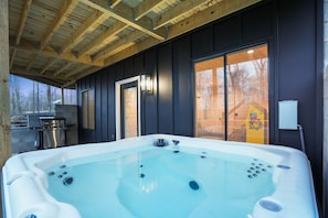 A hot tub in a cabin with a wooden ceiling and a large window.