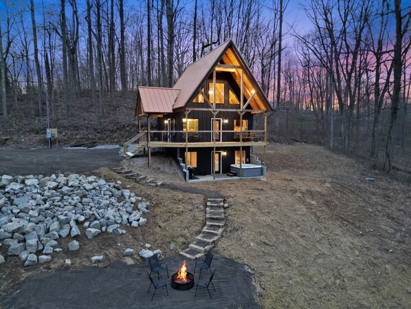 A wooden cabin with a metal roof, a fire pit, and outdoor seating.