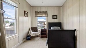 A bedroom with a bed, a chair, a window, and a ceiling fan. - Spacious 6-bedroom house in lovely Corpus Christi 1 block from Ocean Dr. (Corpus Christi)