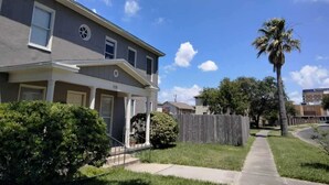 A two-story residential building with a covered porch and a fenced yard. - Spacious 6-bedroom house in lovely Corpus Christi 1 block from Ocean Dr. (Corpus Christi)