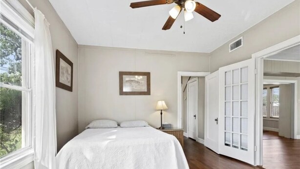 A bedroom with a large bed, a ceiling fan, a window with curtains, and a door leading to another room. - Spacious 6-bedroom house in lovely Corpus Christi 1 block from Ocean Dr. (Corpus Christi)