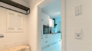 Eine moderne Küche mit weißen Schränken, einem eingebauten Backofen und einer Arbeitsplatte mit Küchengeräten.