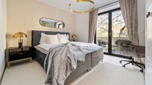 Ein modernes Schlafzimmer mit einem großen Bett, einem Schreibtisch, einem Stuhl und einem Balkon mit Blick.
