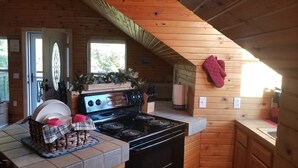 Une cuisine de taille réduite, équipée d’une cuisinière, d’un four et d’une fenêtre.
