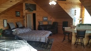 Une cabane chaleureuse avec une chambre à coucher située en mezzanine, un coin repas et une cuisine.