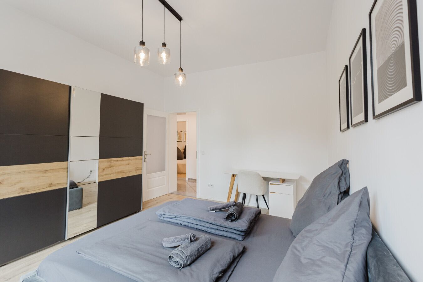 A modern bedroom with a bed, bedside tables, a desk, and a wardrobe.