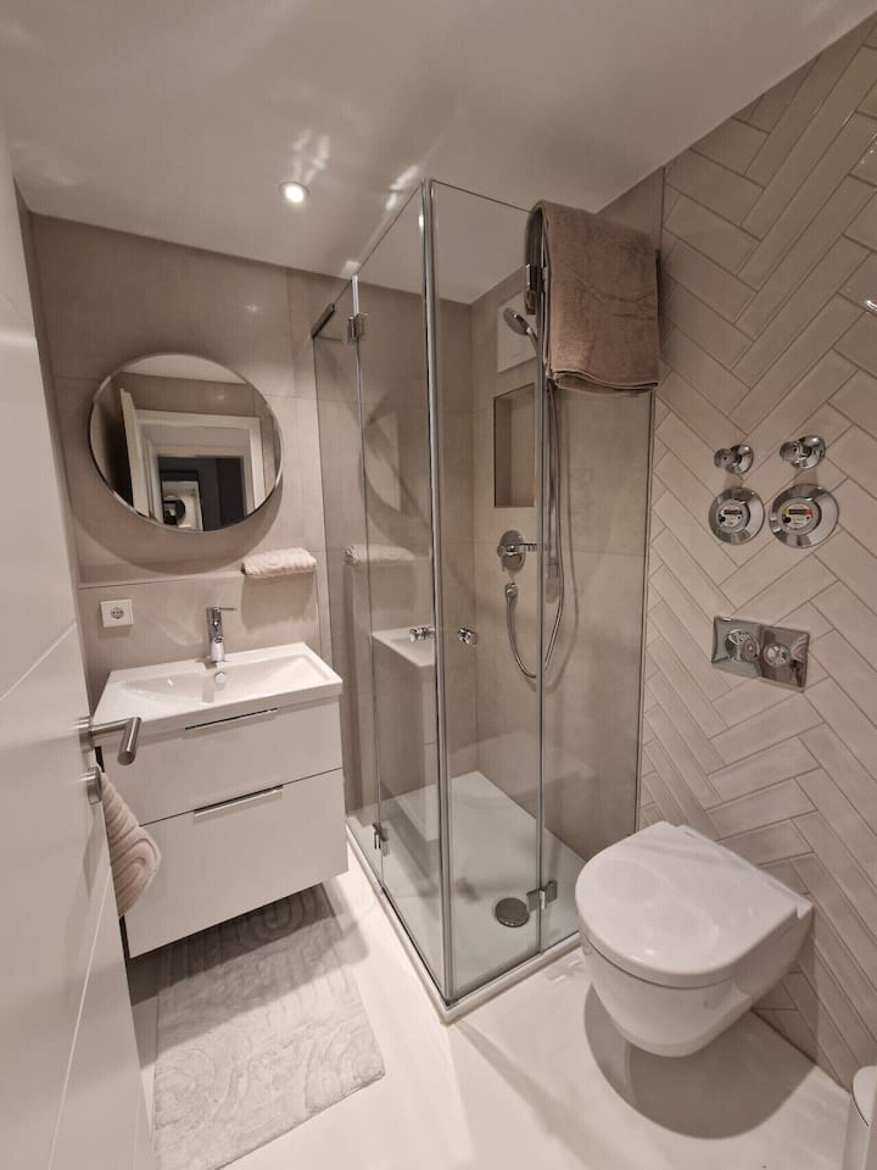 A modern bathroom with a glass-enclosed shower, a white sink, and a toilet.