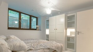 Un dormitorio con cama, armario y lámpara en el techo.