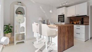 Una cocina moderna con armarios blancos, una isla de madera y taburetes de bar.
