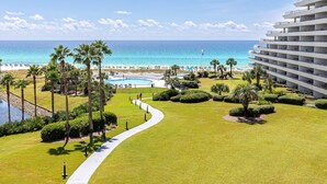 Un complexe hôtelier doté d’une piscine, de palmiers et offrant une vue sur la plage et l’océan.