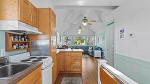 A kitchen with wooden cabinets, a white stove, and a ceiling fan. - Clove Coastal Cottage - Steinhatchee Landing (Steinhatchee)
