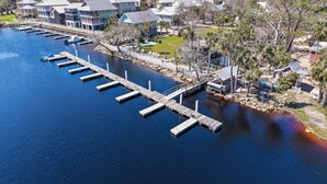 A waterfront property with a dock extending into the water, surrounded by residential buildings and palm trees. - Clove Coastal Cottage - Steinhatchee Landing (Steinhatchee)