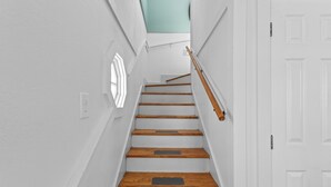 A staircase with wooden steps and white walls, leading to a door with a white frame. - Clove Coastal Cottage - Steinhatchee Landing (Steinhatchee)