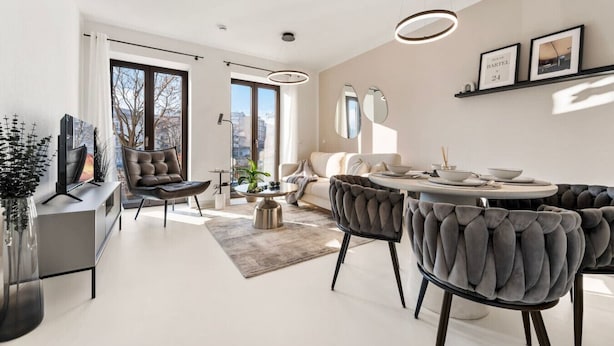 A modern living room with a sofa, chairs, a dining table, and a TV.
