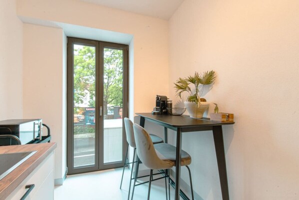Una cocina compacta con comedor, una puerta corrediza de vidrio que da al exterior y una pequeña mesa con sillas.
