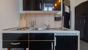 A modern kitchen with black cabinets, a stainless steel sink, and a built-in dishwasher. - Travelbase/Monteurswohnung Anklam (Anklam)