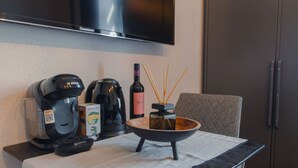 A kitchenette with a coffee maker, kettle, and a bottle of wine on a table. - Travelbase/Monteurswohnung Anklam (Anklam)