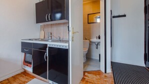 A compact kitchen with a sink, cabinets, and a microwave. Adjacent is a small bathroom with a toilet and sink. - Travelbase/Monteurswohnung Anklam (Anklam)