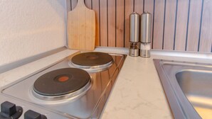 A kitchen with two induction cooktops, a wooden cutting board, and two salt shakers. - Travelbase/Monteurswohnung Anklam (Anklam)