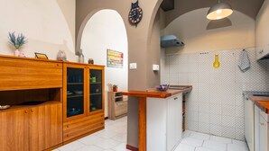 A kitchen with wooden cabinets, a central island, and a clock on the wall. - Apartment 'Musa Giardini Naxos' with Terrace, Garden and Air Conditioning (Giardini Naxos)