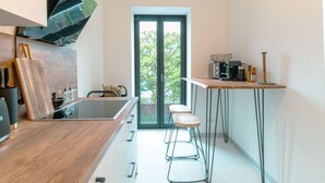 Een moderne keuken met een centraal eiland, barkrukken en een koffieapparaat.