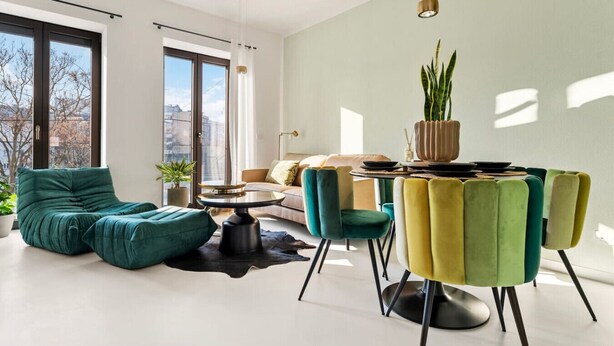 Een moderne woonkamer met een bank, stoelen, een eettafel en een potplant.