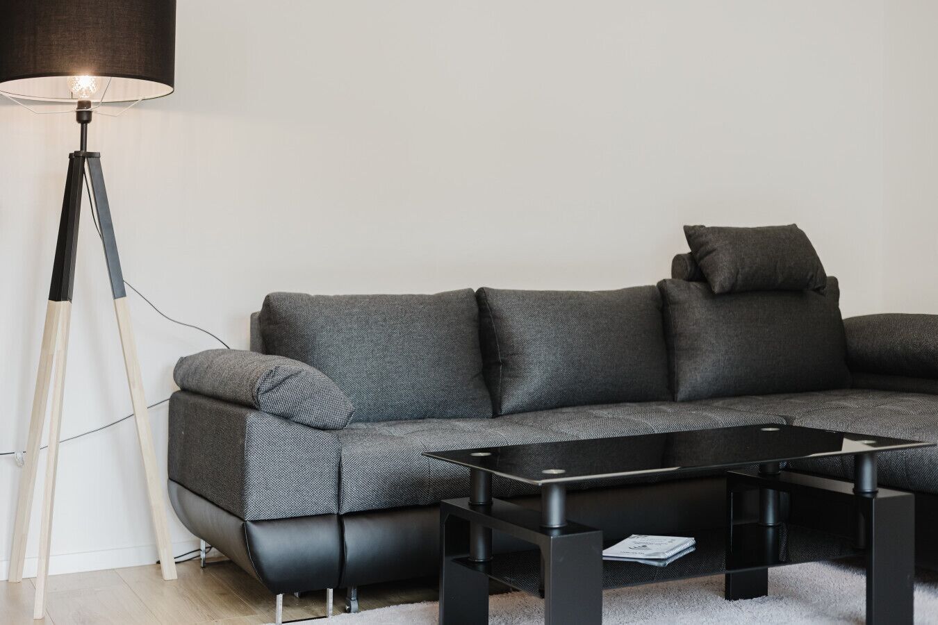 Un salon moderne avec un canapé gris, une table basse noire et un lampadaire.
